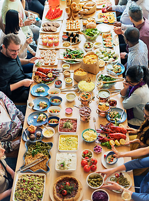 Many people around a table, eating at a Cuisine Buffet Party Concept.
