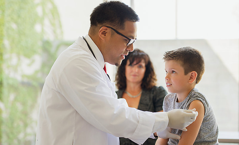Paediatrician gives a flu shot to a young boy.