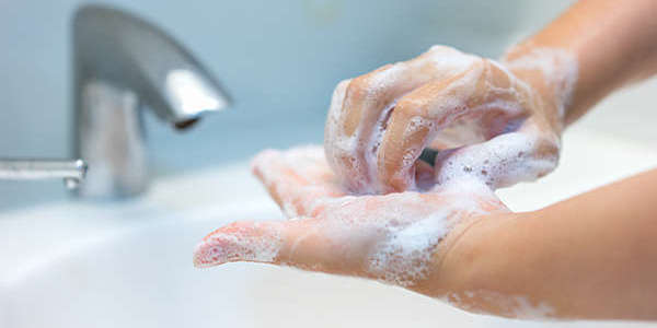 Hands of a woman washing her hands in a bathroom sink.