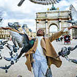 France, Paris, Young smiling woman among doves flying in front of Triumph arch of Carousel.