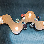 Business people sitting at a curved wooden desk.