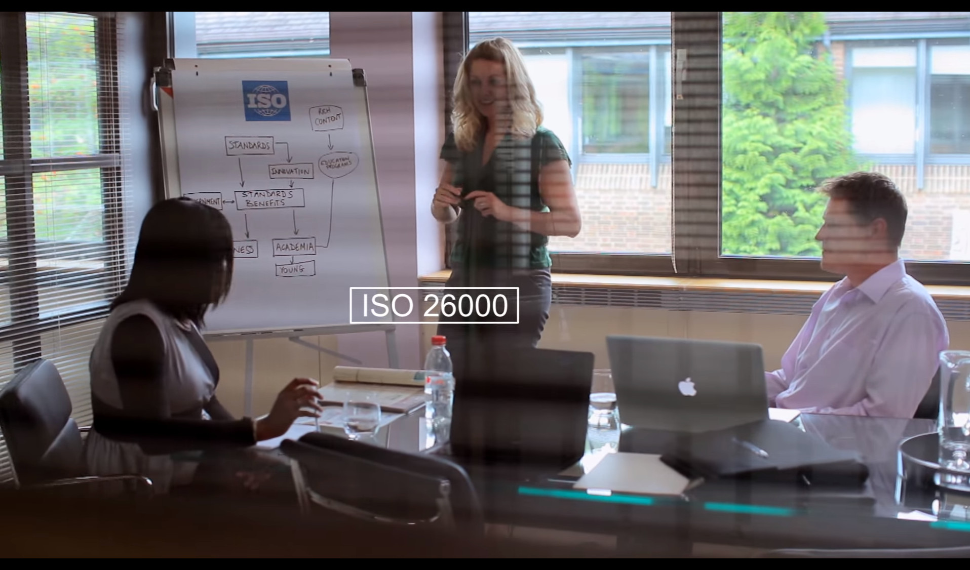 People in office look at flip-chart and discuss ISO 26000